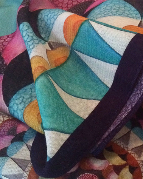 Colorful fabric with geometric patterns and a hand holding a purple object.